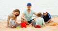 Happy family of five sitting at sandy beach