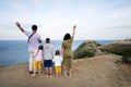 Happy family of five tanding on top of a mountain and looking at the sea and hands up. Cape Emine, Black sea coast, Bulgaria Royalty Free Stock Photo