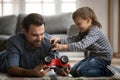 Happy family fixing car, enjoying playtime together at home.