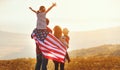 Happy family with flag of america USA at sunset outdoors