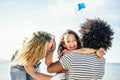 Happy family flying with kite and having fun on the beach - Multi ethnic couple playing with cheerful daughter on summer vacation Royalty Free Stock Photo