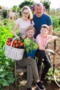 Happy family of four with basket of ripe vegetables on field