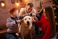 A happy family of four and a dog celebrate the New Year. Dad, mom, son and daughter love the dog and have fun against the Royalty Free Stock Photo