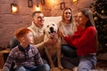 A happy family of four and a dog celebrate the New Year. Dad, mom, son and daughter love the dog and have fun against the Royalty Free Stock Photo