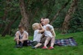 Happy family of four having picnic at the park. Mother and three children sitting on picnic blanket. Weekend outdoors Royalty Free Stock Photo