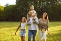 Happy family of four with kids walking in summer park enjoying beautiful nature. Royalty Free Stock Photo