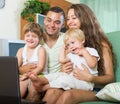 Happy family of four looking laptop