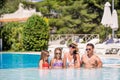 Happy family of four in outdoors swimming pool Royalty Free Stock Photo