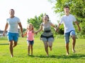 Happy family of four running on grass at summer park