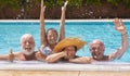 Happy family of four senior people floating in outdoor swimming pool raising splashes of water. They smile relaxed on vacation Royalty Free Stock Photo
