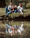 Happy family of four sitting on the grass on the lake Royalty Free Stock Photo