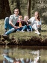 Happy family of four sitting on the grass on the lake Royalty Free Stock Photo