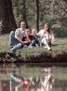 Happy family of four sitting on the grass on the lake Royalty Free Stock Photo
