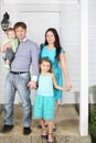 Happy family of four stand on porch of new white house. Royalty Free Stock Photo