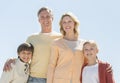 Happy Family Of Four Standing Against Clear Blue Sky Royalty Free Stock Photo