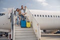 Happy family of four standing on airstairs, getting off the plane on a daytime Royalty Free Stock Photo