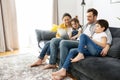 Happy family of four using laptop sitting on the sofa in cozy apartment, parents and two kids talking with relatives Royalty Free Stock Photo