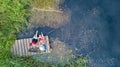 Happy family and friends fishing together outdoors near lake in summer, aerial top view