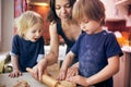 Happy family funny boys and their mom are preparing the dough, bake cookies in the kitchen at home