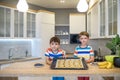 Happy family funny kids are preparing the dough, bake cookies in the kitchen. Put berry and blueberry in all biscuits Royalty Free Stock Photo