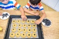 Happy family funny kids are preparing the dough, bake cookies in the kitchen. Put berry and blueberry in all biscuits Royalty Free Stock Photo