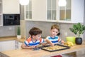 Happy family funny kids are preparing the dough, bake cookies in the kitchen. Put berry and blueberry in all biscuits Royalty Free Stock Photo