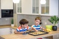 Happy family funny kids are preparing the dough, bake cookies in the kitchen. Put berry and blueberry in all biscuits Royalty Free Stock Photo