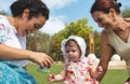 A happy family of 3 generations, baby, mother and grandmother sitting on the grass and playing outdoors Royalty Free Stock Photo