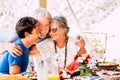 Happy family with grandfathers and grandson together hugging and smilng with joy - people have fun and love - lunch together at