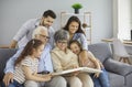 Happy family grandparents with twin granddaughters and their parents browse the family photo album. Royalty Free Stock Photo