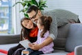 Happy family handsome Asian father, little daughter girls sitting on sofa in cozy living room at home, doing activity together, Royalty Free Stock Photo