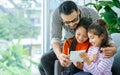 Happy family handsome Asian father, little daughter girls sitting on sofa in cozy living room at home, doing activity together, Royalty Free Stock Photo