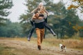 Man carries his wife and daughter on his back at forest path next to dog during walk Royalty Free Stock Photo