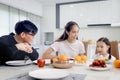 Happy family has meal in dining room. Parents, mother father and kid daughter sit at dining table and have fun during breakfast or Royalty Free Stock Photo