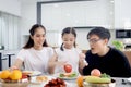 Happy family has meal in dining room. Parents, mother father and kid daughter sit at dining table and have fun during breakfast or Royalty Free Stock Photo