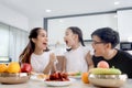 Happy family has meal in dining room. Parents, mother father and kid daughter sit at dining table and have fun during breakfast or Royalty Free Stock Photo