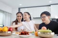 Happy family has meal in dining room. Parents, mother father and kid daughter sit at dining table and have fun during breakfast or Royalty Free Stock Photo