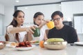 Happy family has meal in dining room. Parents, mother father and kid daughter sit at dining table and have fun during breakfast or Royalty Free Stock Photo