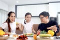 Happy family has meal in dining room. Parents, mother father and kid daughter sit at dining table and have fun during breakfast or Royalty Free Stock Photo