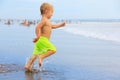 Child run with splashes by water pool along sea surf Royalty Free Stock Photo