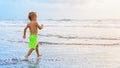 Child run with splashes by water pool along sea surf Royalty Free Stock Photo