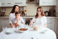 Happy family having breakfast at home. Mother with two kids eating in the morning in modern white kitchen Royalty Free Stock Photo