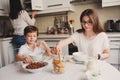 Happy family having breakfast at home. Mother with two kids eating in the morning in modern white kitchen Royalty Free Stock Photo