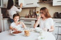 Happy family having breakfast at home. Mother with two kids eating in the morning in modern white kitchen Royalty Free Stock Photo