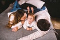 Happy family is having fun in bedroom. Enjoying being together. Parents are tickling their little son while lying in bed Royalty Free Stock Photo