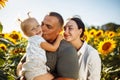 Happy family having fun in the field of sunflowers. Father and mother holding their daughter in the hands and smile. Summer season Royalty Free Stock Photo