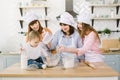 Happy family having fun in the kitchen. Grandmother and her daughters and little baby girl kneading dough together in Royalty Free Stock Photo