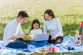 Happy family having fun outdoor on picnic using laptop computer technologies relaxing to open song Royalty Free Stock Photo