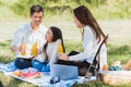 Happy family having fun outdoor sitting on picnic blanket drinking orange juice from glass bottle Royalty Free Stock Photo