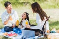 Happy family having fun outdoor sitting on picnic blanket drinking orange juice from glass bottle Royalty Free Stock Photo